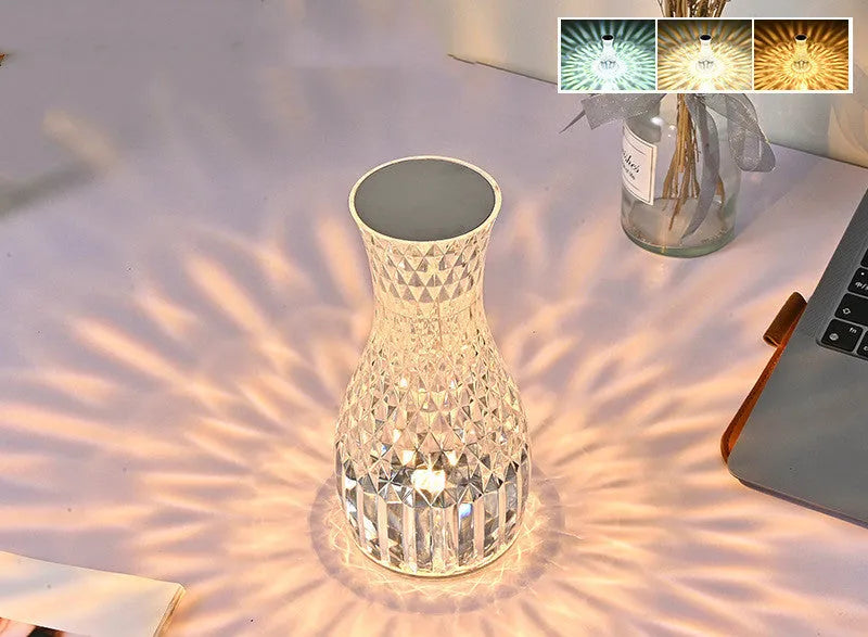 Clear plastic vase-shaped crystal bedside lamp with LED lights on a wooden table.