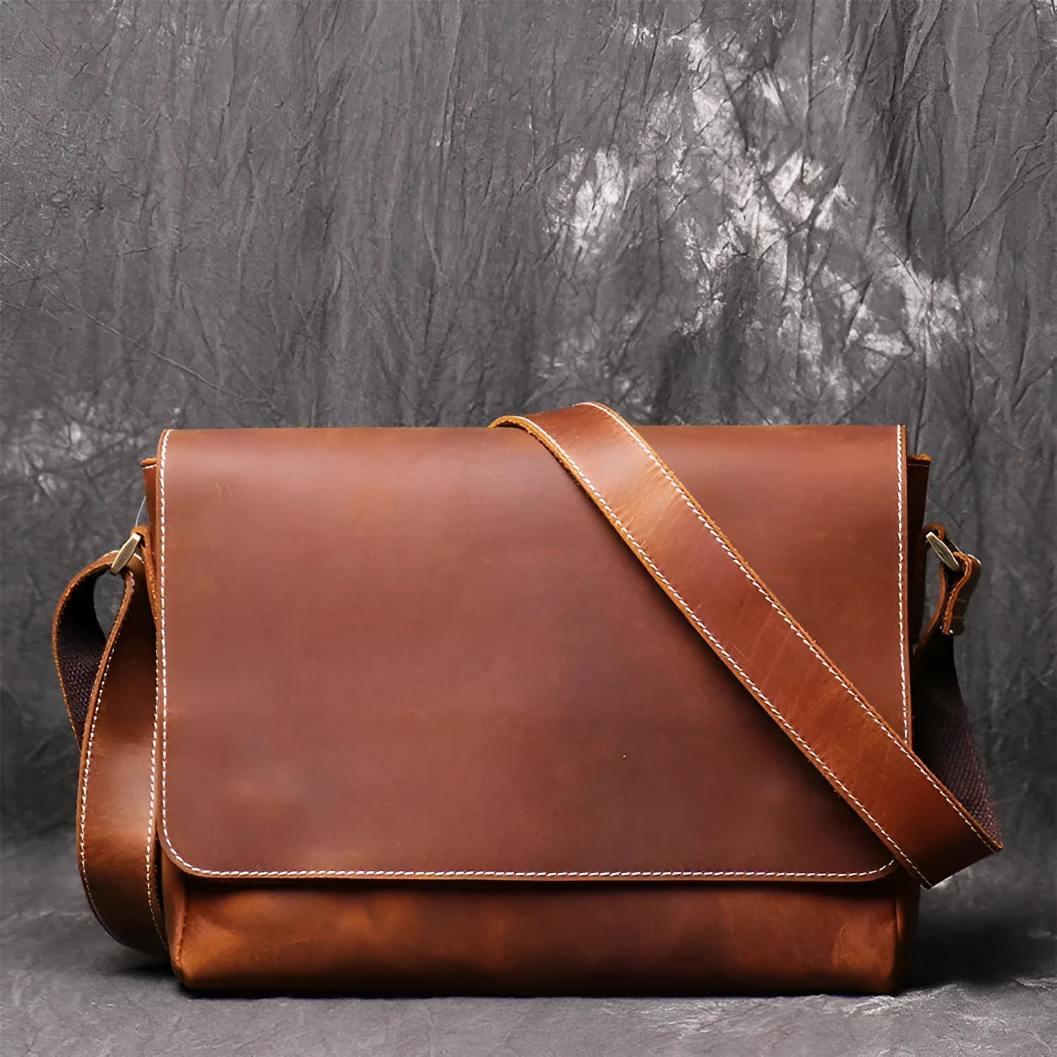 Vintage brown cowhide leather messenger bag with a shoulder strap, shown open to reveal internal ID, phone, and zipper pockets.