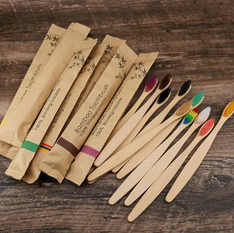 Set of ten bamboo toothbrushes with charcoal-infused bristles in assorted colours on a white background.