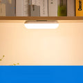 White and black portable magnetic LED desk lamp with adjustable dimming on a wooden desk