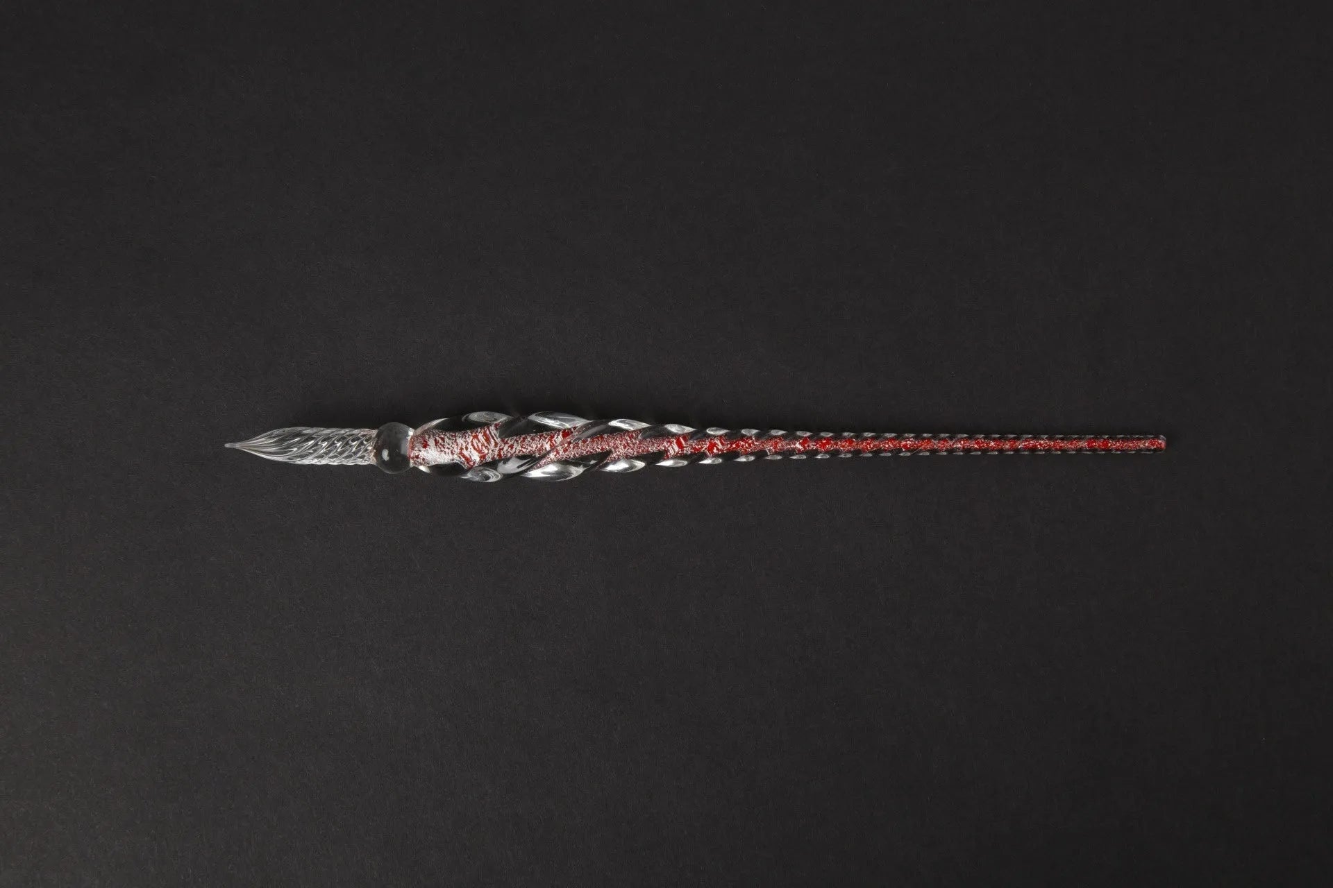 Hand-blown glass crystal pen with coloured ink in a transparent barrel on a gift box.