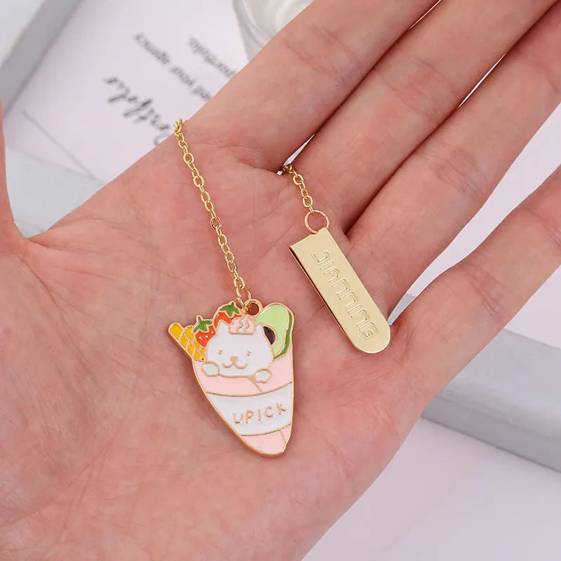 Metal cartoon cat bookmark with food-themed designs including strawberry cake and fruit roll styles