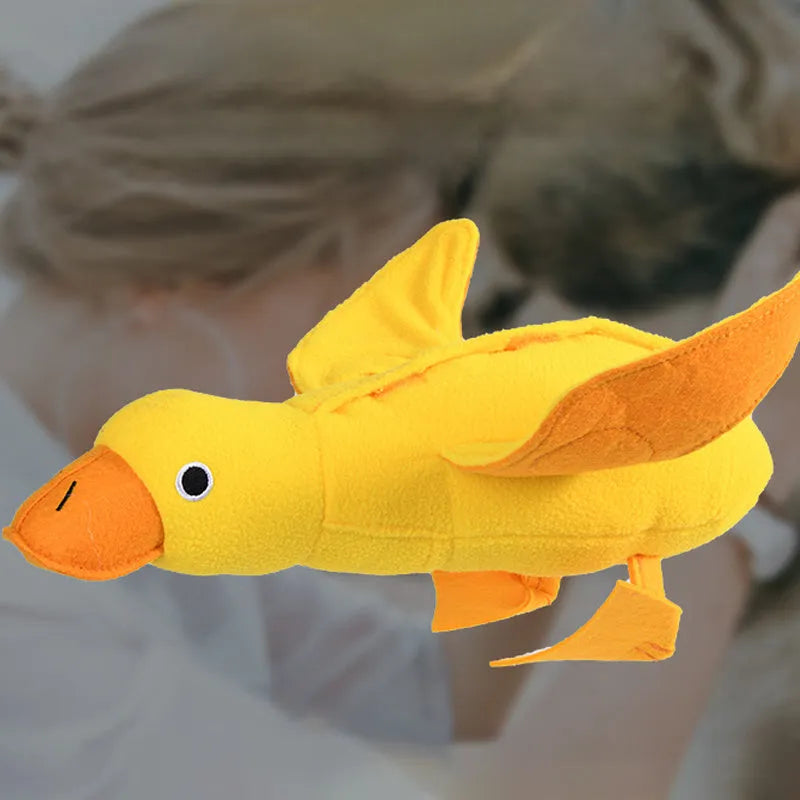 Yellow plush teddy bear dog toy with a small duck doll attached, showing food dispensing holes.
