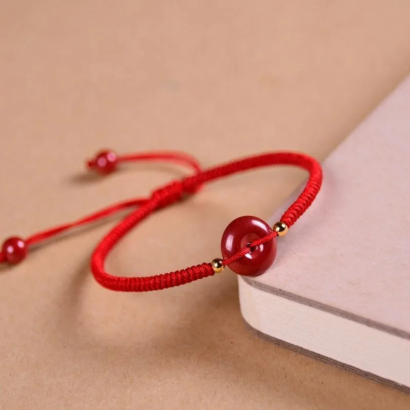 Heart-shaped cinnabar bead on an adjustable knot rope bracelet with a decorative peace buckle closure.