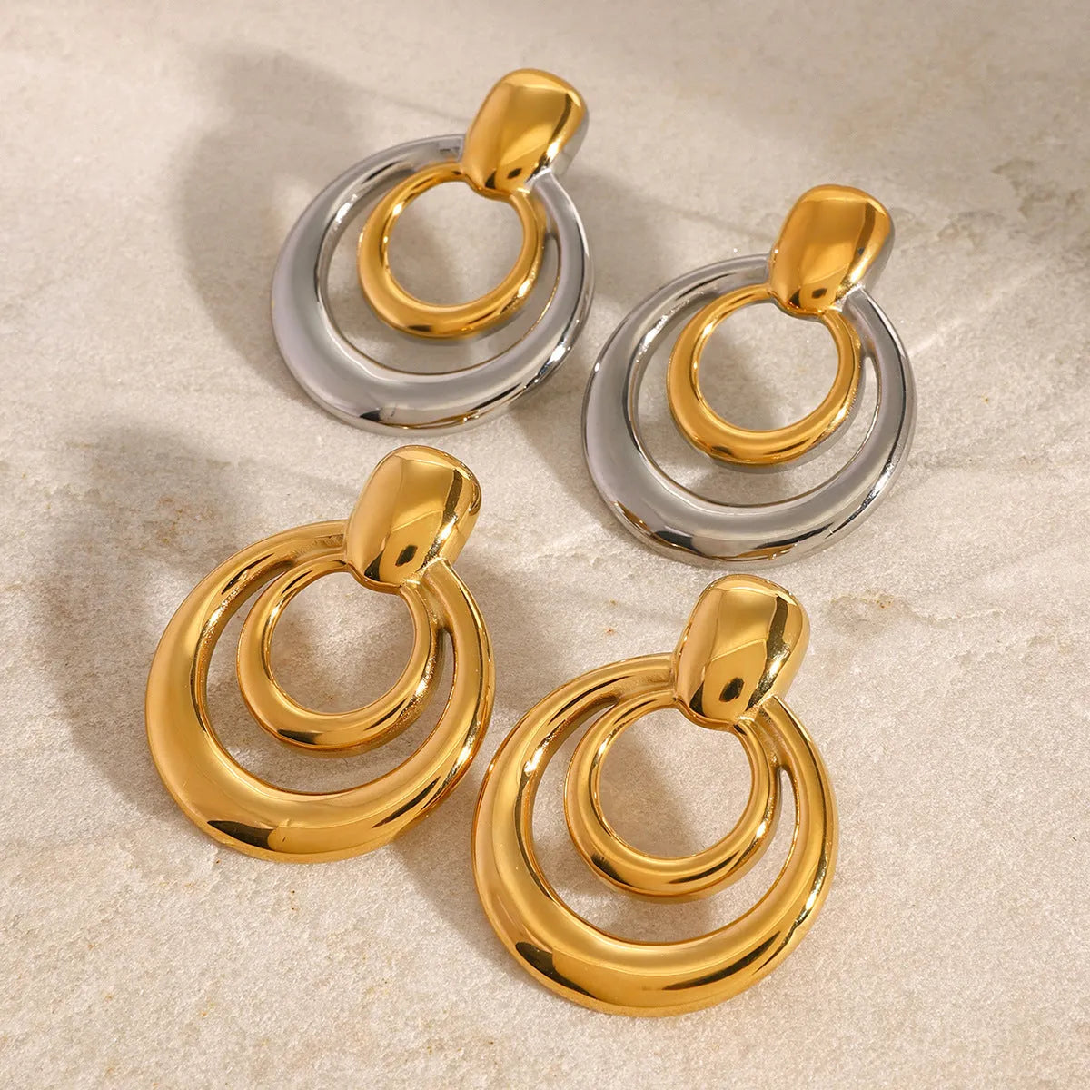 Golden round double layer hollow stud earrings with geometric design on white background