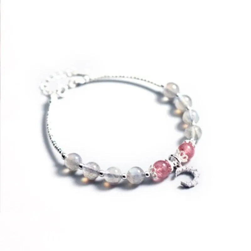 Natural moonstone bracelet with round beads, a crescent moon charm, and an adjustable silver chain on a wrist.