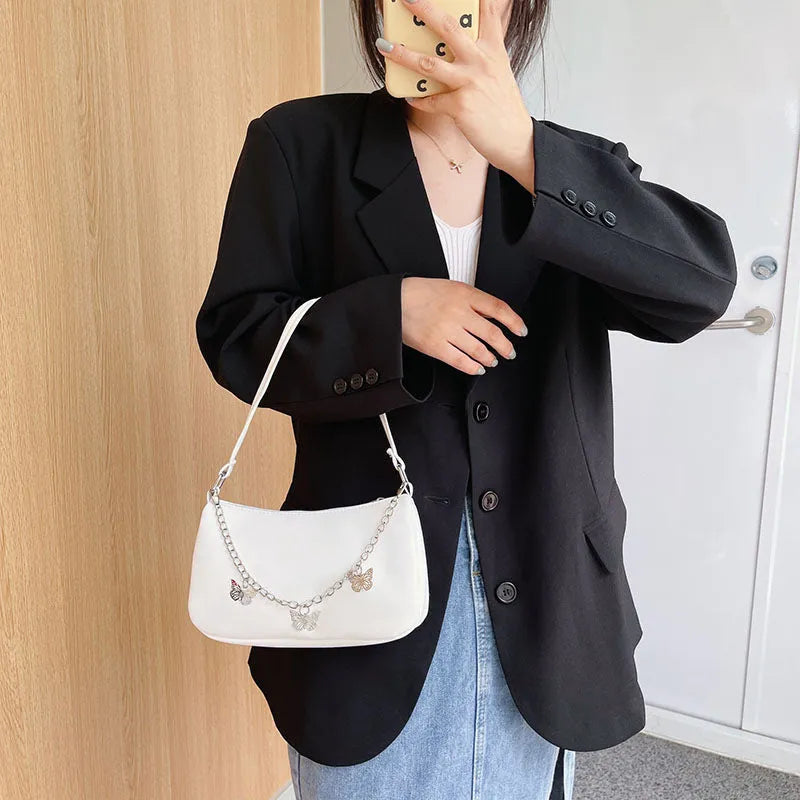 Square black PU leather crossbody bag with a butterfly chain strap and external structured pocket.