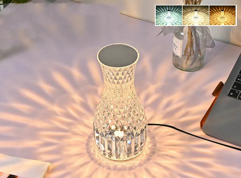 Clear plastic vase-shaped crystal bedside lamp with LED lights on a wooden table.