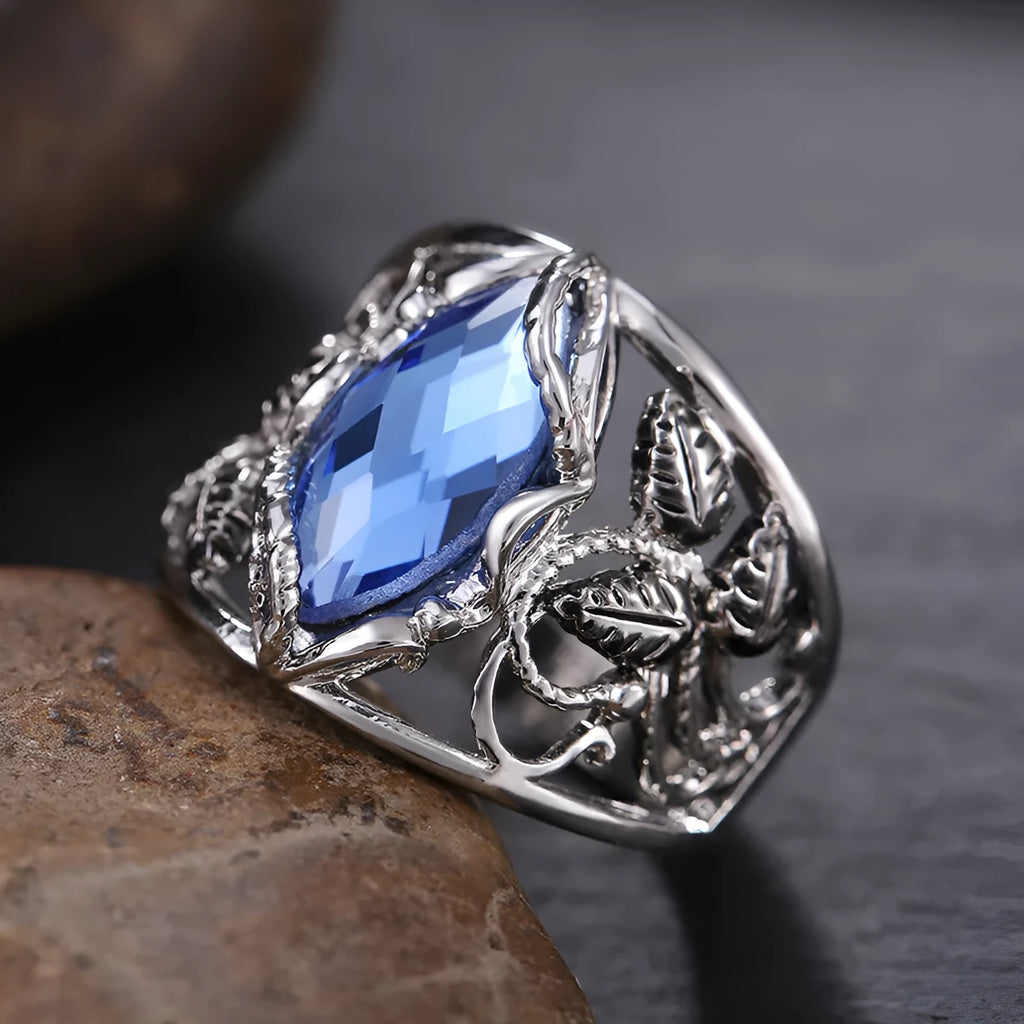 Close-up of a blue crystal horse eye-shaped geometric alloy ring on a person's finger.