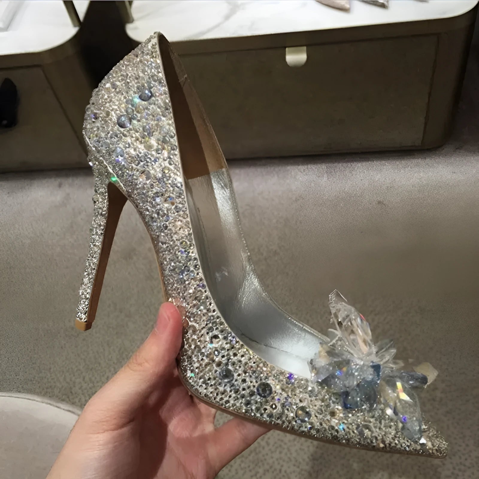 Gold women's high heels with pointed toe, rhinestone details, bow and stiletto heel on a plain background.