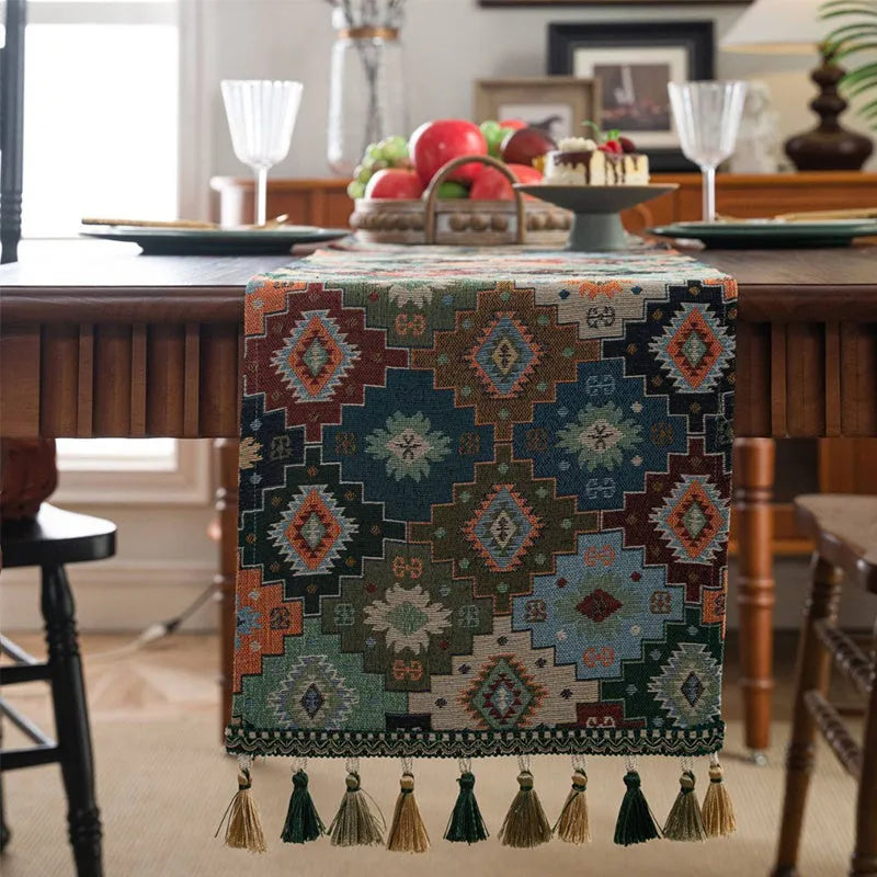 Dark blue and white striped jacquard table runner with tassel trim laid on a wooden dining table.