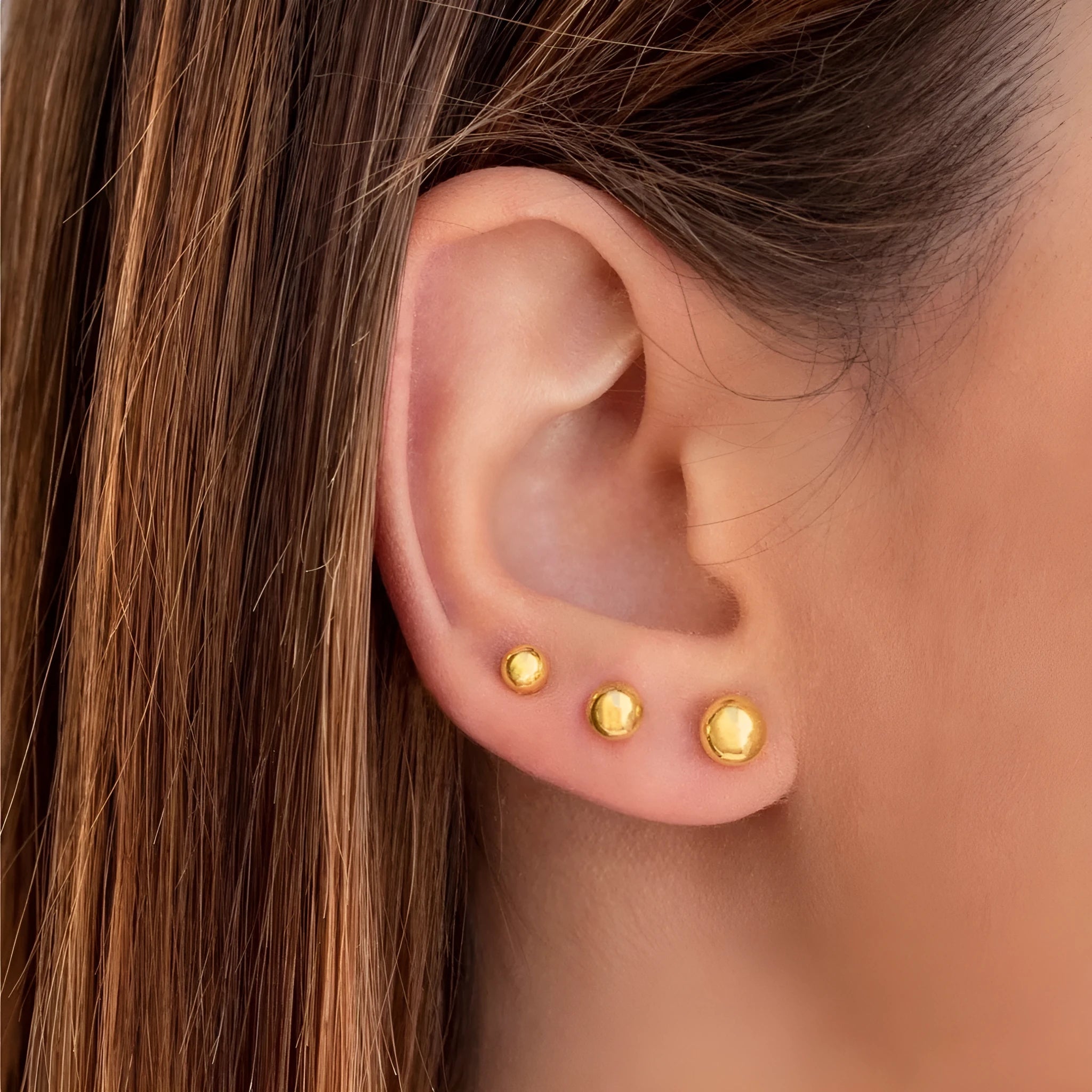 Stainless steel ball stud earrings in gold and silver finishes on a grey background.