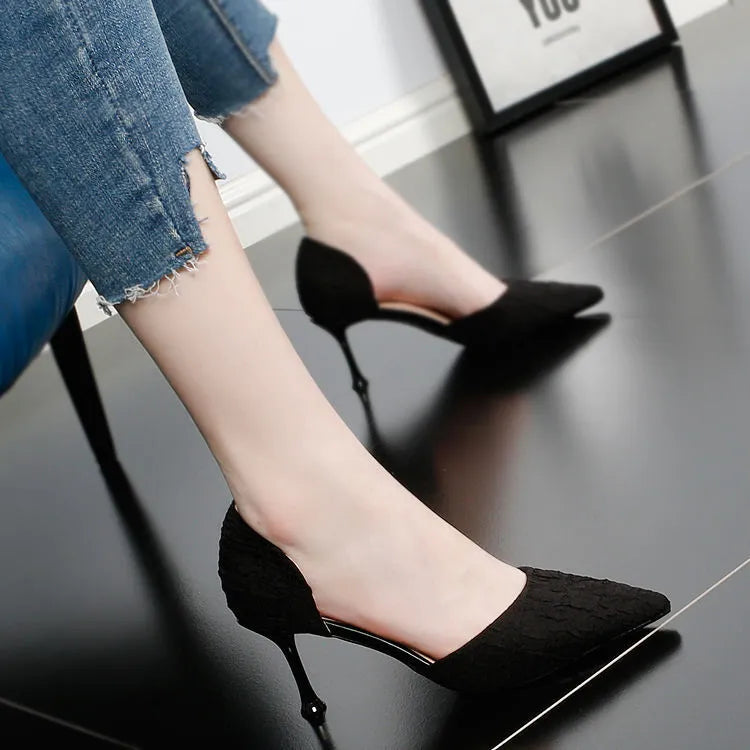 Women's black pointed leather high heel shoes with a stiletto heel on a plain background.
