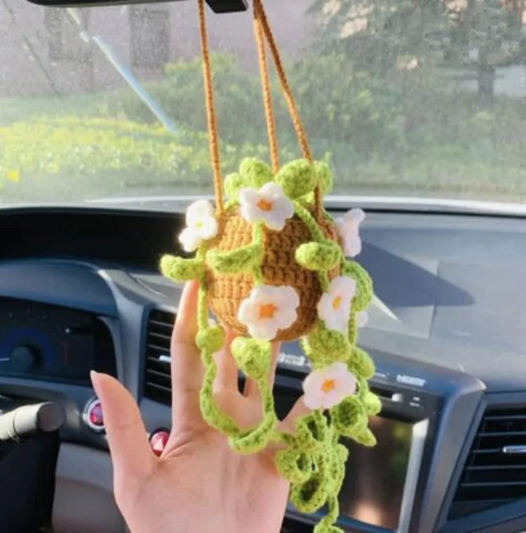 Green and white crochet wool car plant decoration with hanging rope on car dashboard