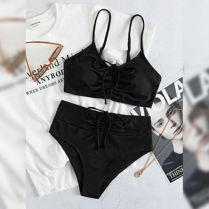Black high-waisted bikini swimsuit for women with sleeveless top and shorts on a neutral background.