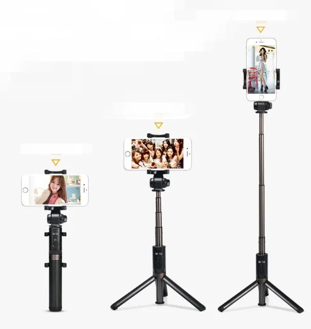 Black Bluetooth selfie stick tripod with extended rod, phone clamp, and deployed legs next to a smartphone