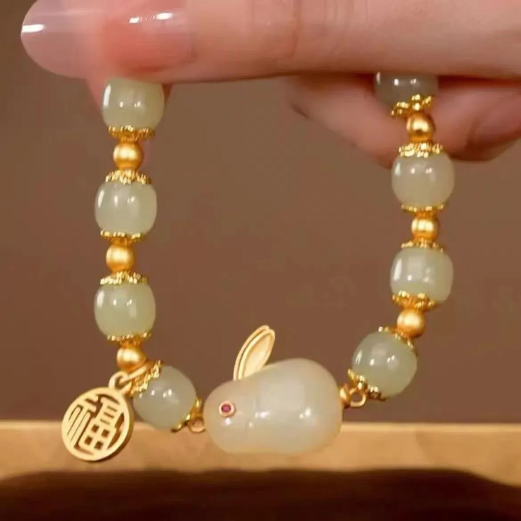 Women's black bracelet with green jade hare charm, fu character, and lily motif detail.