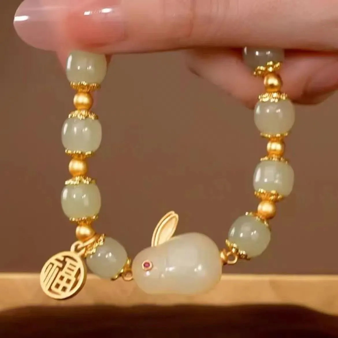 Women's black bracelet with green jade hare charm, fu character, and lily motif detail.