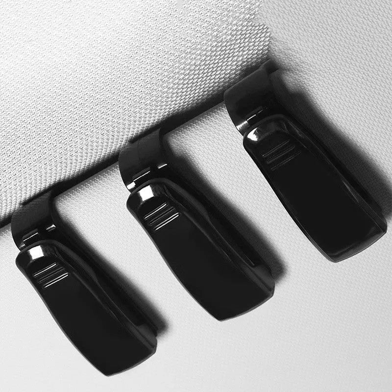Black plastic car sunshade clip for holding glasses and cards on a vehicle visor.