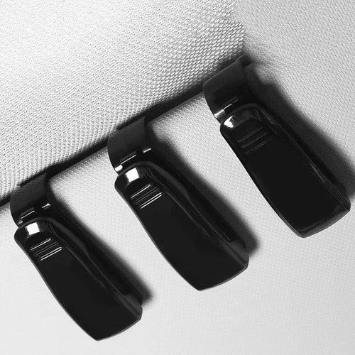 Black plastic car sunshade clip for holding glasses and cards on a vehicle visor.