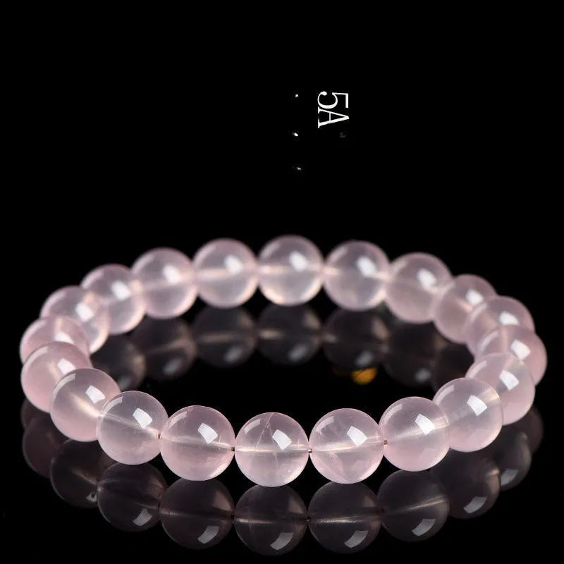 Close-up of a polished natural starlight crystal round bead bracelet in pink, showing single circle design.