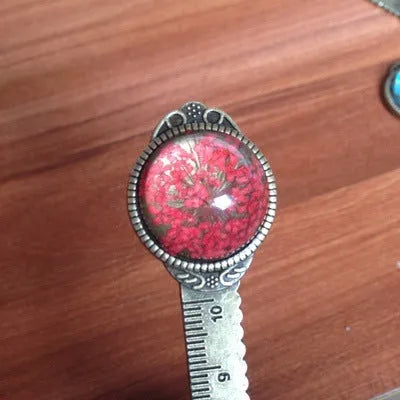 Handmade dried flower bookmark with lace flowers, daffodils, and clover, measuring 12cm long, on a book.