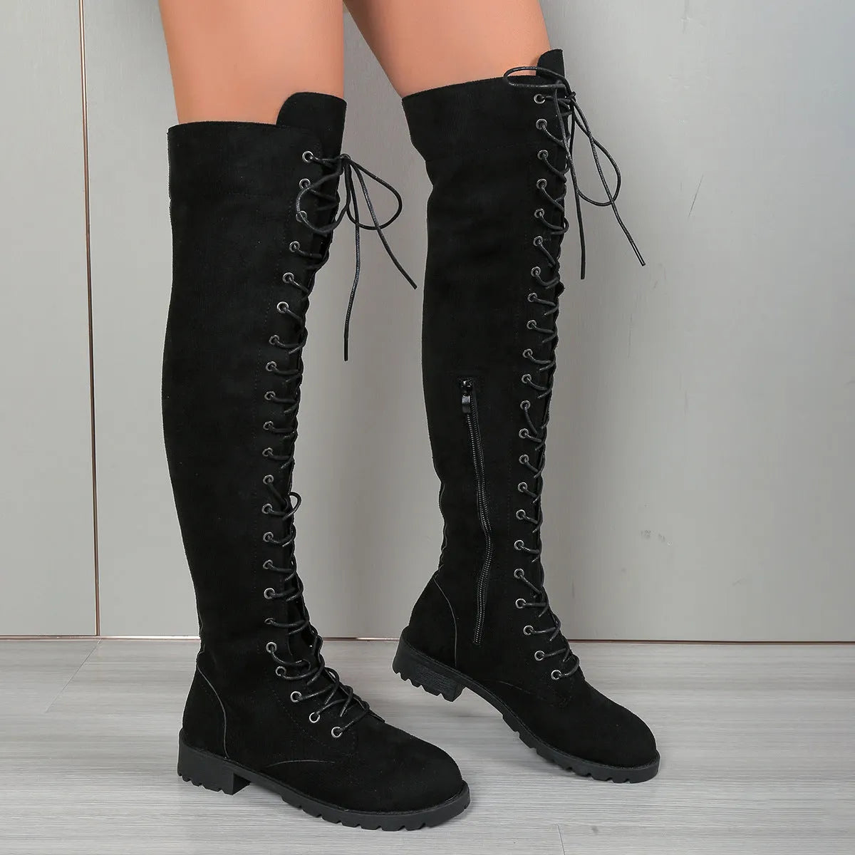 Women's black lace-up over-the-knee boots with flat heel and round toe on a neutral background