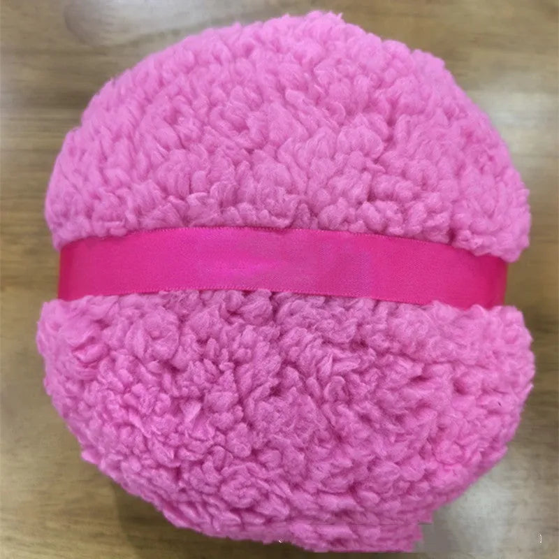 Large oval white plush powder puff for makeup on a plain background.