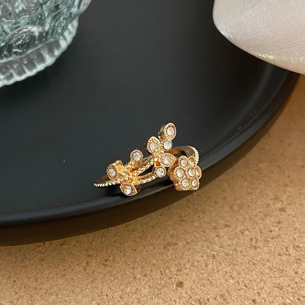 Gold and white women's open ring with floral leaf design and diamond treatment.