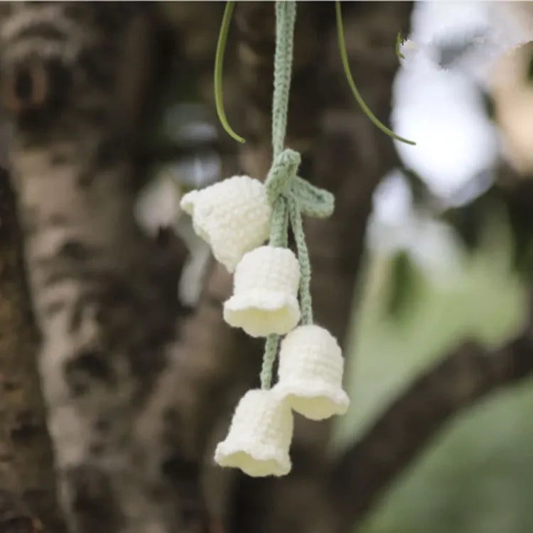 Green and white crochet wool car plant decoration with hanging rope on car dashboard