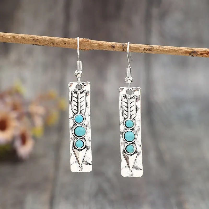 Silver long drop earrings with turquoise inlay and a geometric shape.
