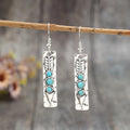 Silver long drop earrings with turquoise inlay and a geometric shape.