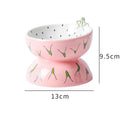 Ceramic raised cat feeder bowl in orange patterned design on a white surface.