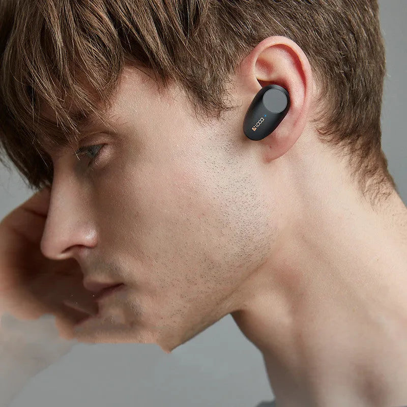 Black wireless Bluetooth headset with charging stand on a table