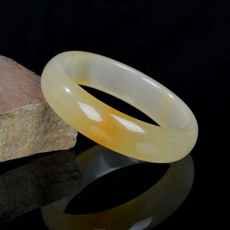 Natural light green jade bracelet in Chinese style, shown on a wrist, with a polished surface.