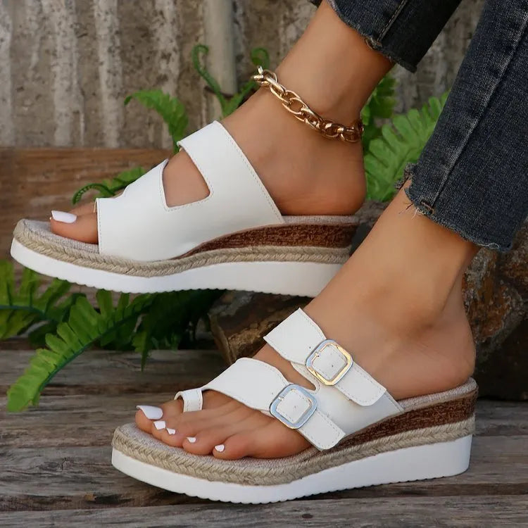 White patent leather wedge sandals with woven upper and peep toe design on a neutral background