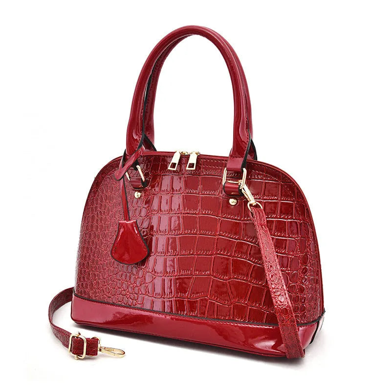 Shiny black PU crossbody bag with a structured shell shape and an adjustable strap.
