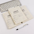 White A5 loose-leaf notebook inner pages with monthly plan layout on a plain background