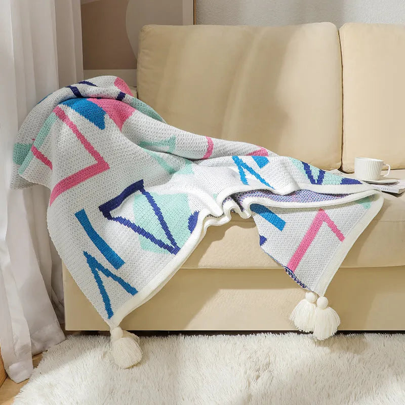 Acrylic sofa blanket with tassels in geometric pattern colour option on a sofa