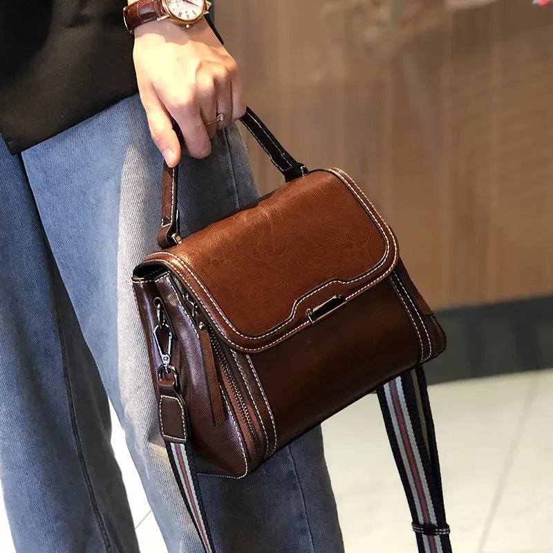 Women's brown genuine oil wax leather messenger bag showing front view with double straps and visible sewing details.