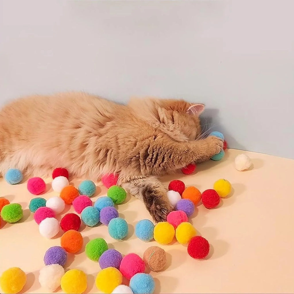 Cat toy ball launcher gun in hand with 20 soft plush pom pom balls for interactive fetch play
