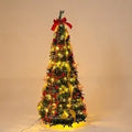 Green velvet foldable telescopic Christmas tree with warm lights on floor-standing base in indoor room setting