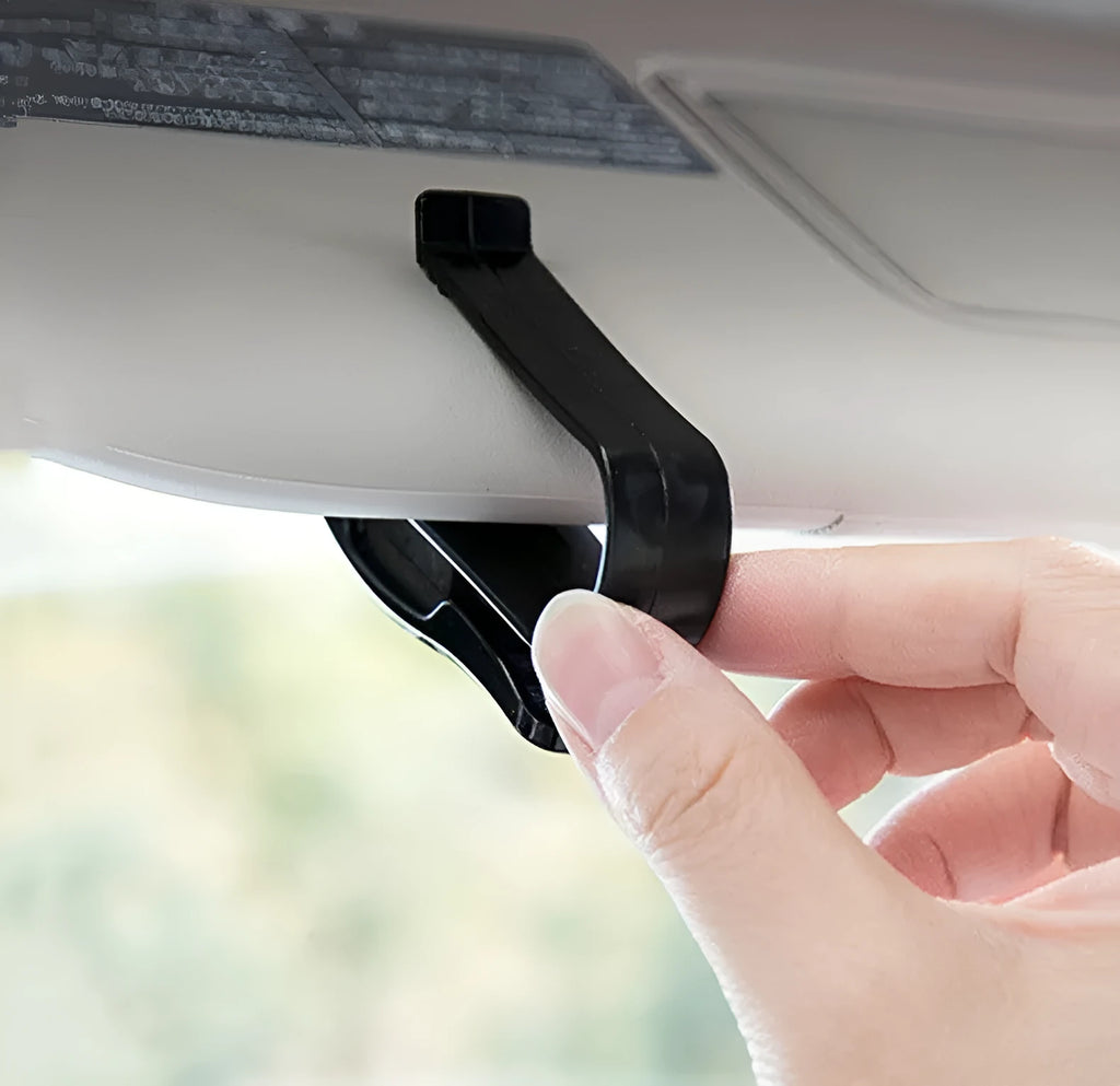 Black plastic car sunshade clip for holding glasses and cards on a vehicle visor.