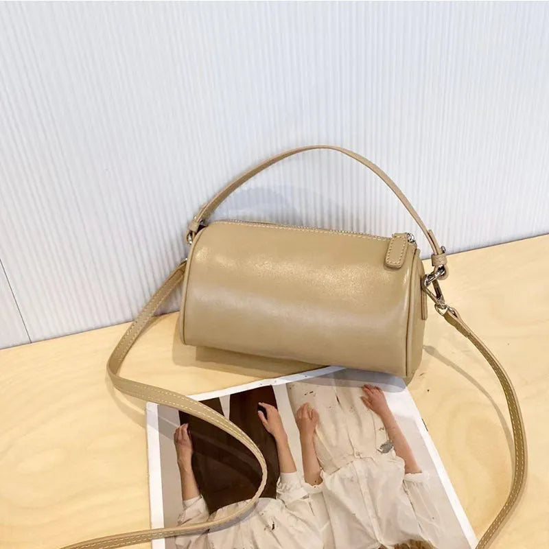 A soft genuine leather cylindrical crossbody bag for mobile phones in street style.