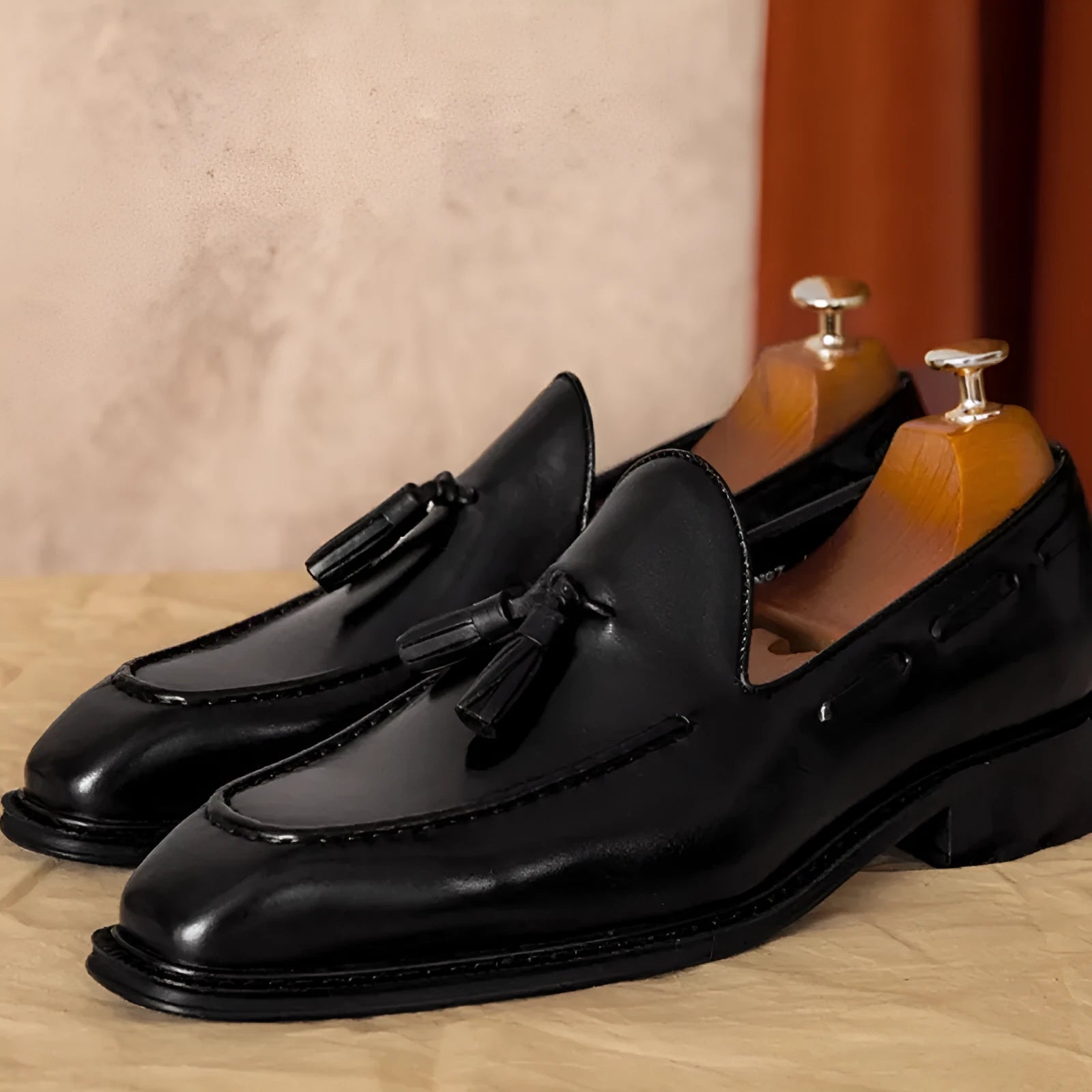 Men's black and brown British-style leather slip-on loafers showing polished leather upper and rubber sole
