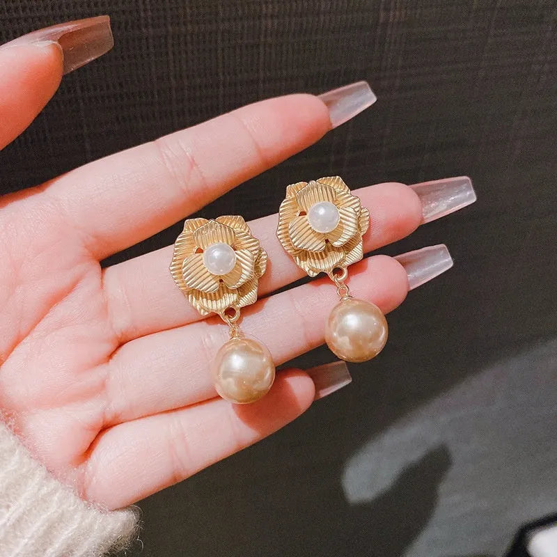 Gold flower stud earrings with a pearl, opal, and needle rose design on a white background.