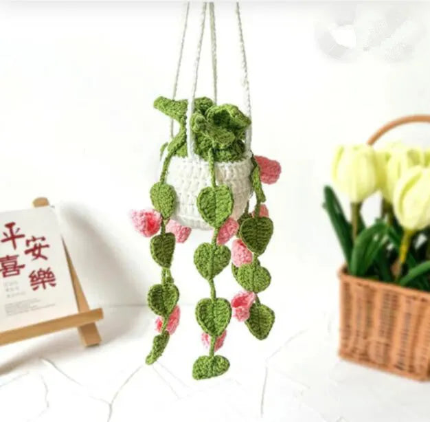 Green and white crochet wool car plant decoration with hanging rope on car dashboard