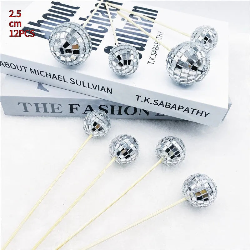 Glass disco ball cake decoration with wooden stick on a cake, showing reflective surface.