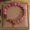 Pink and white natural stone bracelet with lotus flower pendant and tassel.