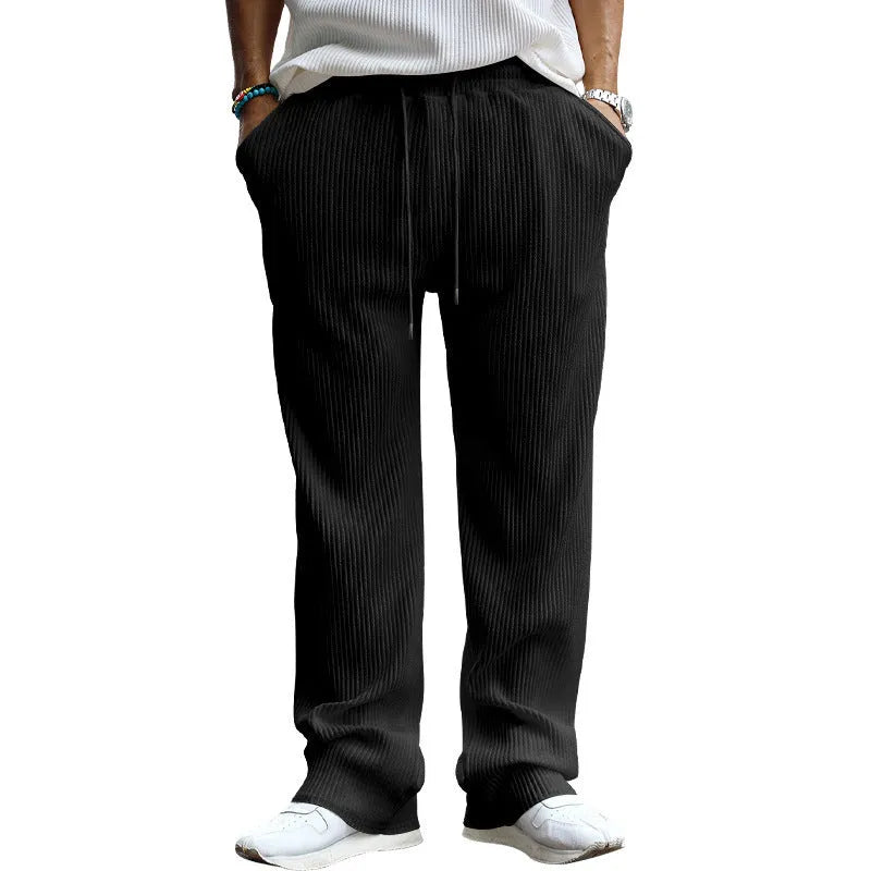 Man wearing casual loose-fit high-waist straight-leg striped trousers in a solid colour.